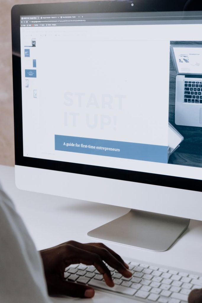 Person working on a website design for first-time entrepreneurs on a desktop computer.